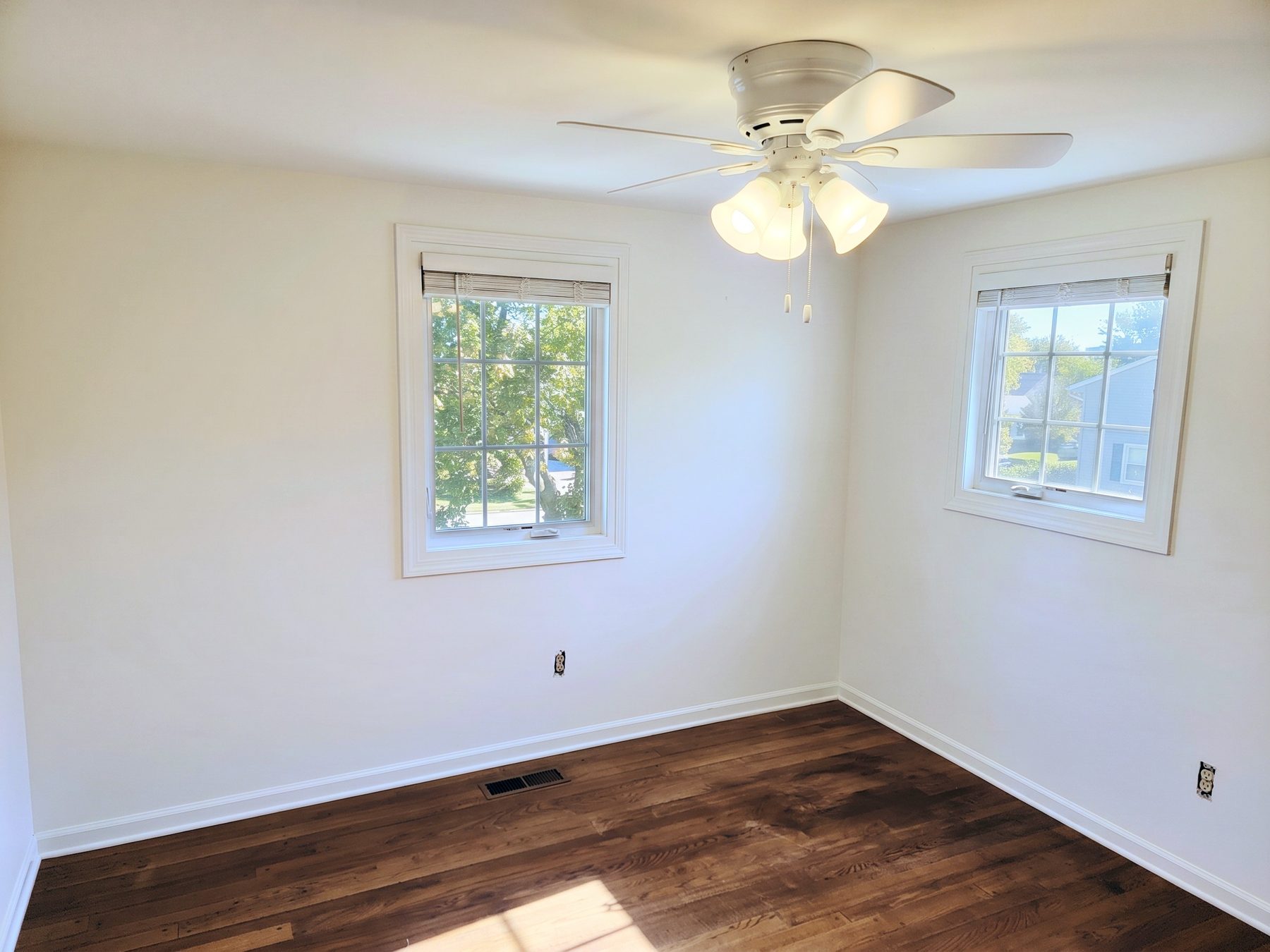 A freshly painted bedroom with two windows and a ceiling fan — interior painting by Home Strategy LLC